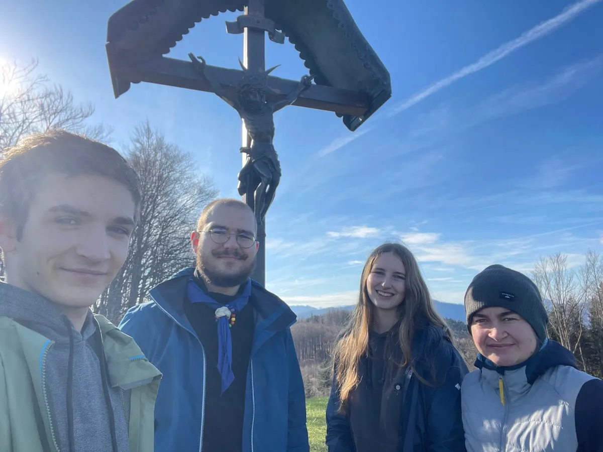 Vier RaRo machen ein Selfie vor einem Wegkreuz unter blauem Himmel