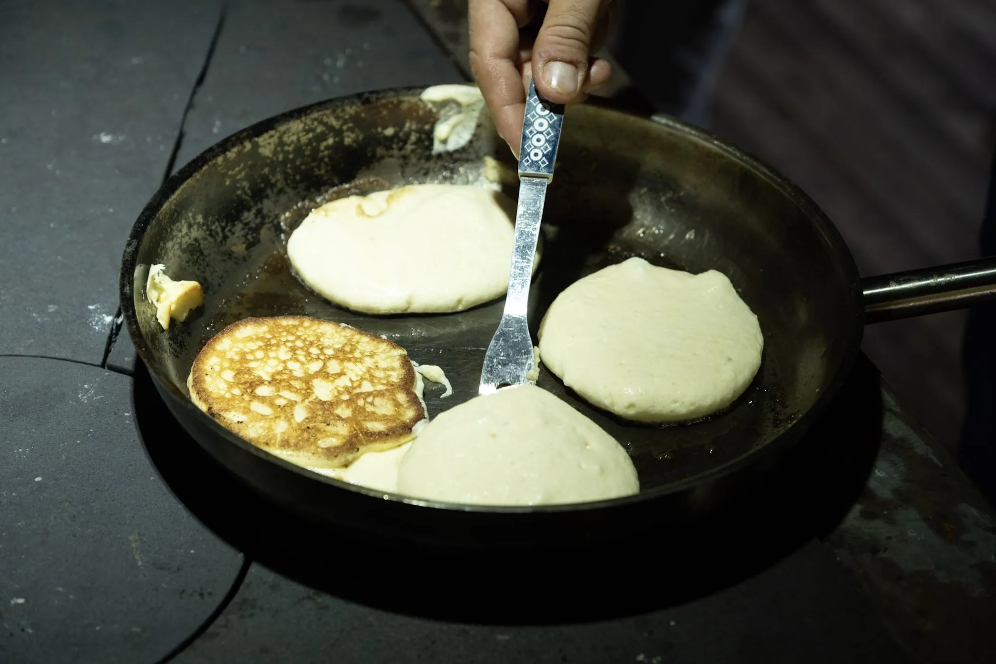 Pfannkuchen braten in einer Pfanne auf dem Holzherd.