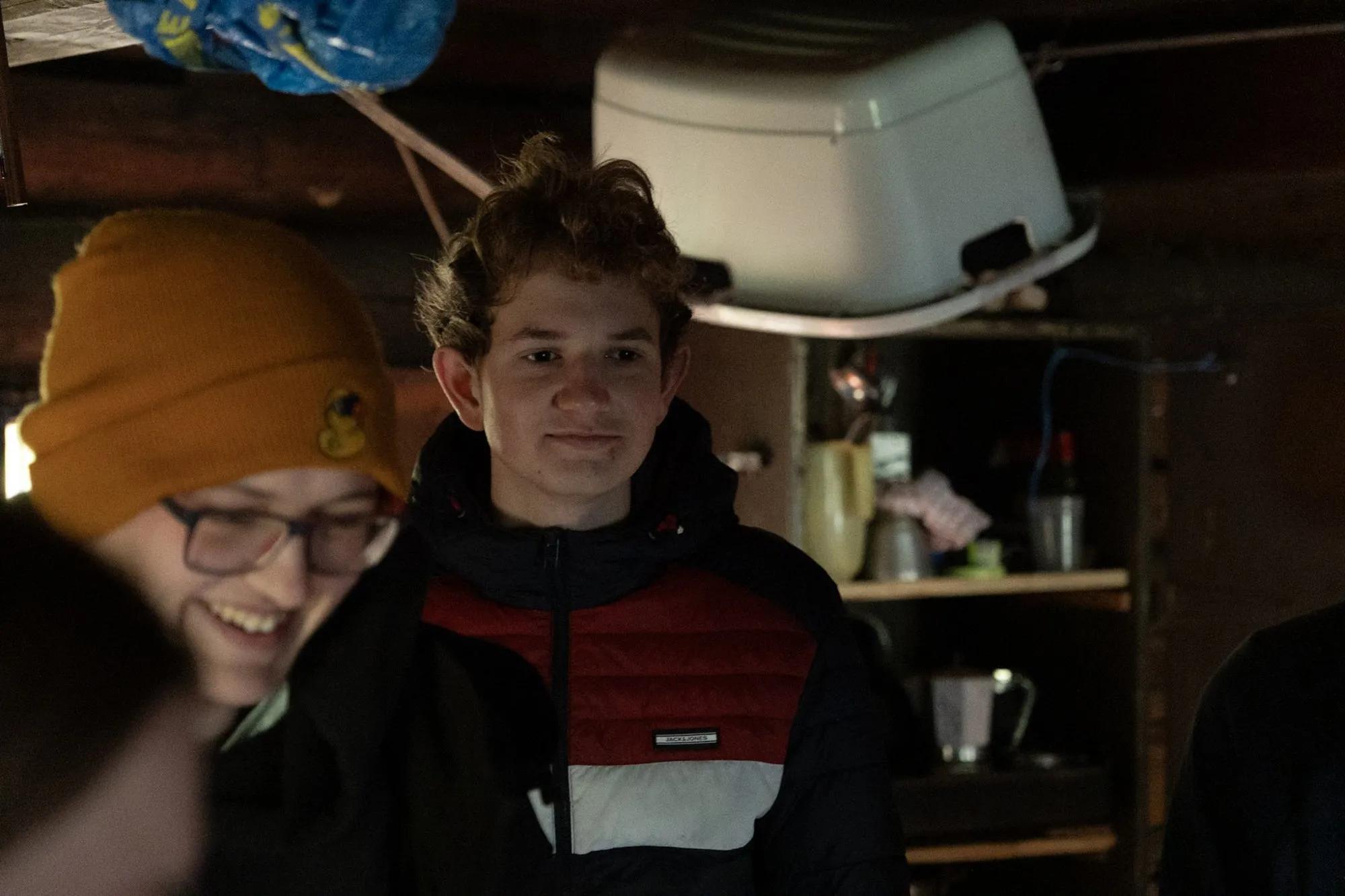 Zwei RaRo stehen am Abend lächelnd in der dunklen Hütte.