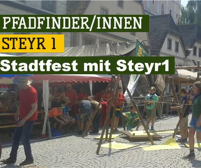 Unser Stand am Steyrer Stadtplatz mit Pfadfinder*innen und einem Holzaufbau, darüber der Schriftzug „Stadtfest mit Steyr1“